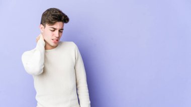 Mor arka planda izole olmuş genç beyaz bir adam stresten dolayı boynu ağrıyor, masaj yapıyor ve elle dokunuyor..