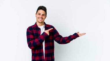 Beyaz arka planda izole edilmiş genç beyaz bir adam, palmiye üzerinde bir fotokopi alanı tutarken heyecanlı..