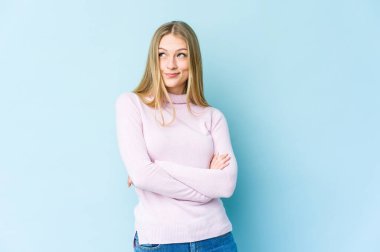 Mavi arka planda izole edilmiş genç sarışın kadın hedeflere ve amaçlara ulaşmayı hayal ediyor.