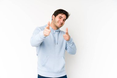 Beyaz arka planda izole edilmiş genç adam parmaklarıyla ön tarafı işaret ediyor..