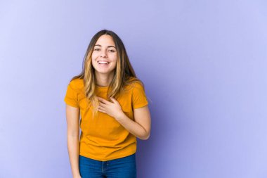 Mor arka planda soyutlanmış beyaz bir kadın yüksek sesle gülüyor ve elini göğsüne koyuyor..