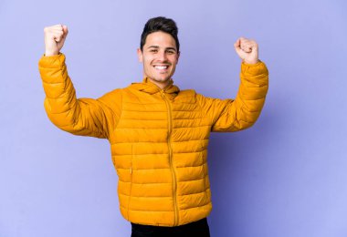 Mor arka planda izole edilmiş genç beyaz adam tasasız ve heyecanlı bir şekilde tezahürat yapıyor. Zafer konsepti.