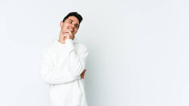 Beyaz arka planda izole edilmiş genç beyaz bir adam rahatlamış bir şeyin fotokopi odasına baktığını düşünüyor..