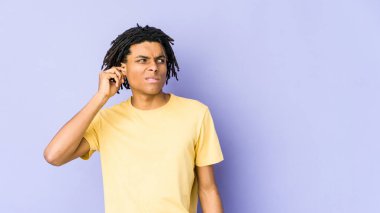Genç Afrikalı Amerikalı Rasta adam kulaklarını parmaklarıyla kapatıyor, gürültülü bir ortam yüzünden stresli ve çaresiz..