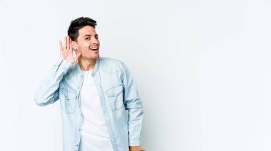 Beyaz arka planda izole edilmiş genç beyaz adam bir dedikoduyu dinlemeye çalışıyor..