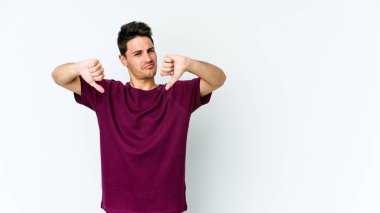 Beyaz arka planda izole edilmiş genç beyaz adam baş parmağını aşağı gösteriyor, hayal kırıklığı konsepti..