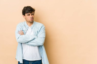 Hoşnutsuzca kaşlarını çatan, kollarını kavuşturan genç havalı bir adam..