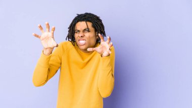 Rasta saç stili giymiş genç siyah bir adam pençelerini bir kediyi taklit ederken gösteriyor, agresif bir hareket..