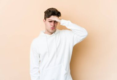 Beyaz tenli genç adam bej arka planda izole edilmiş tapınaklara dokunuyor ve baş ağrısı çekiyor..