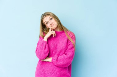 Mavi arka planda izole edilmiş genç sarışın kadın tekrarlanan bir görevden yoruldu..