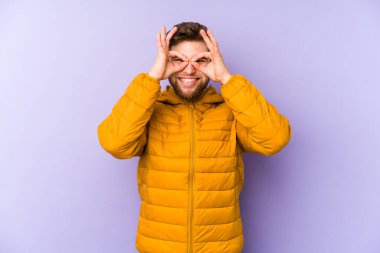 Mor arka planda izole edilmiş genç beyaz adam gözlerinde sorun olmadığını gösteriyor.