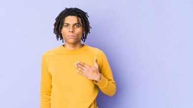 Rasta saç stili giyen genç siyah adam yemin ediyor, elini göğsüne koyuyor..