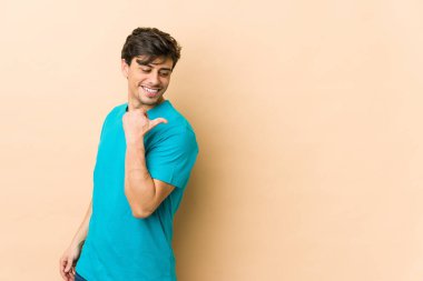 Genç havalı adam başparmağıyla işaret ediyor, gülüyor ve kaygısız..