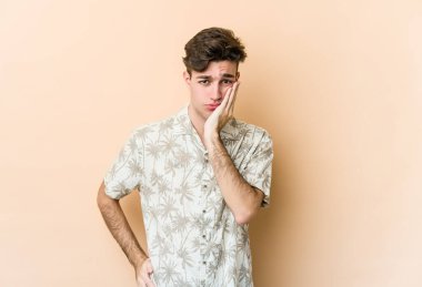 Bej arka planda izole edilmiş, üzgün ve dalgın hisseden, fotokopi alanına bakan genç beyaz bir adam..