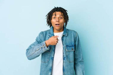 Kot ceket giyen genç siyah adam parmağını göstererek şaşırdı, geniş bir gülümsemeyle..