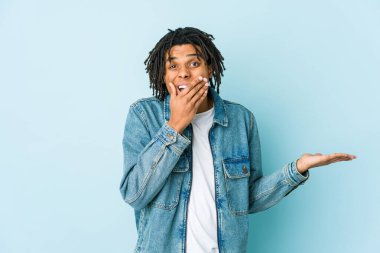 Kot ceket giyen genç siyahi bir adam avuç içinde fotokopi alanı tutuyor, el üstünde tutuyor. Şaşırmış ve mutlu..