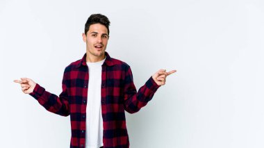 Beyaz arka planda izole edilmiş genç beyaz bir adam farklı kopya alanlarını gösteriyor, birini seçiyor, parmaklarıyla gösteriyor..