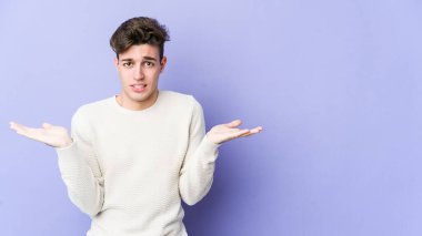 Mor arka planda izole edilmiş genç beyaz bir adam. Kafası karışmış ve omuz silkiyor. Kopya alanını tutmak için..