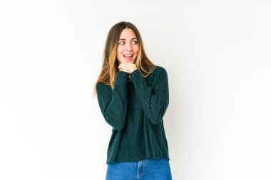 Beyaz arka planda izole edilmiş genç beyaz bir kadın şans için dua ediyor, şaşırmış ve ağzını açıp önüne bakıyor..