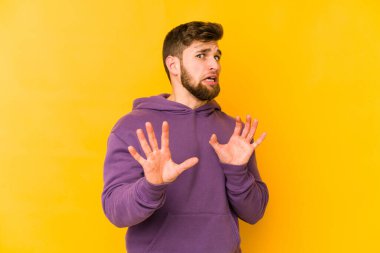Sarı arka planda izole edilmiş genç beyaz adam tiksinti belirtisi gösteren birini reddediyor..