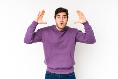 Genç adam beyaz arka planda zaferi ya da başarıyı kutlarken şaşırdı ve şok oldu..