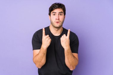Mor arka planda izole edilmiş genç bir adam ağzı açık, üst tarafı işaret ediyor..