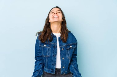 Latin kökenli genç bir kadın izole edilmiş, rahat ve mutlu bir şekilde gülüyor, boynunda dişlerini gösteriyor..