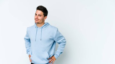 Beyaz arka planda soyutlanmış genç beyaz bir adam kafası karışmış, şüpheli ve güvensiz hissediyor..