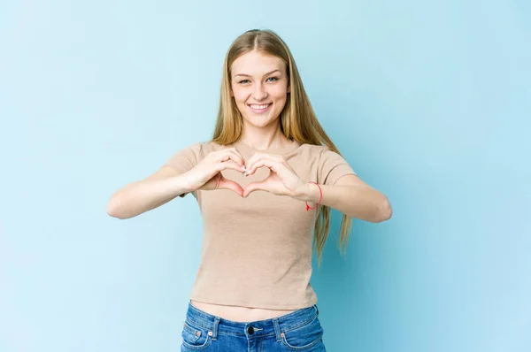 Jovem Loira Isolada Fundo Azul Sorrindo Mostrando Uma Forma Coração — Fotografia de Stock