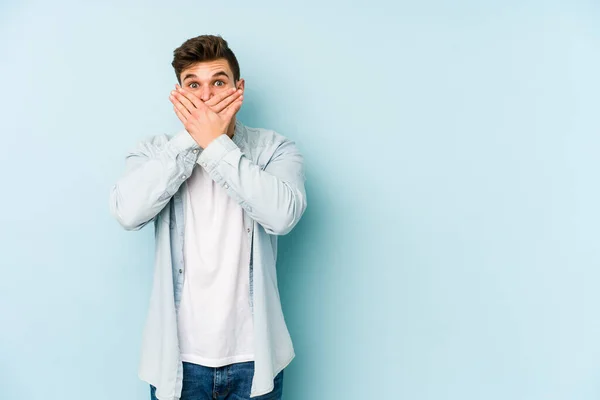 Joven Caucásico Aislado Sobre Fondo Azul Impactado Cubriendo Boca Con —  Fotos de Stock