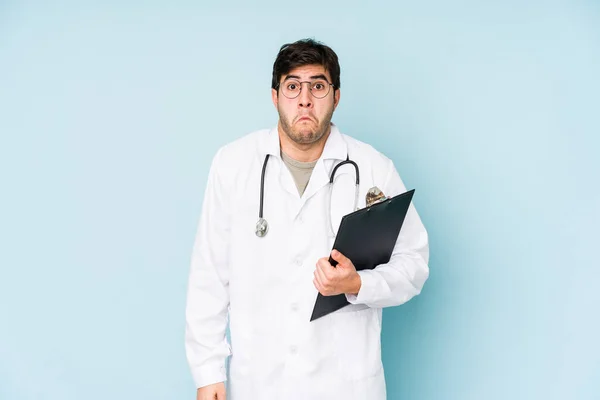 Junger Arzt Auf Blauem Hintergrund Zuckt Mit Den Schultern Und — Stockfoto