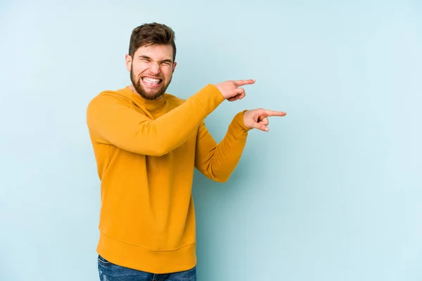 Young Caucasian Man Isolated Blue Background Excited Pointing Forefingers Away — Stock Photo, Image
