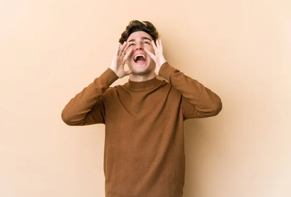 Joven Hombre Caucásico Aislado Sobre Fondo Beige Gritando Emocionado Frente —  Fotos de Stock