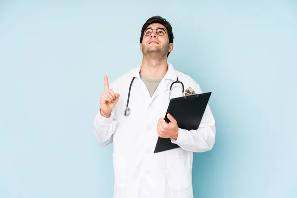 Young Doctor Man Isolated Blue Background Pointing Upside Opened Mouth — Stock Photo, Image