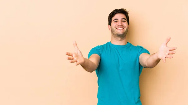 Joven Aislado Sobre Fondo Beige Siente Seguro Dando Abrazo Cámara —  Fotos de Stock