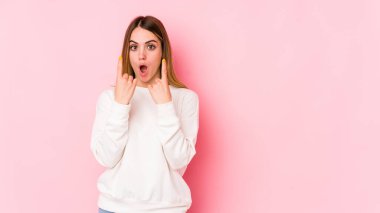Pembe arka planda izole edilmiş beyaz bir kadın ağzı açık bir şekilde üst tarafı işaret ediyor..