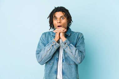 Kot ceket giyen genç siyahi adam şans için dua ediyor, şaşırıyor ve ağzını açıyor..