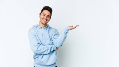 Beyaz arka planda izole edilmiş genç beyaz bir adam bir palmiye üzerinde fotokopi alanı gösteriyor ve belinde başka bir el tutuyor..