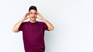 Beyaz arka planda izole genç beyaz adam hoş bir sürpriz alıyor, heyecanlı ve el kaldırıyor..