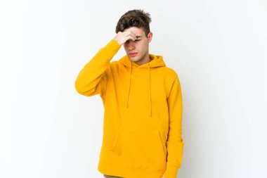 Beyaz arka planda izole olmuş genç beyaz bir adam başı ağrıyor, yüzüne dokunuyor..