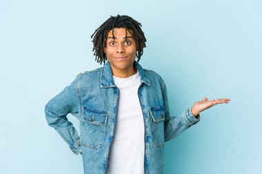 Kot ceket giyen genç siyahi bir adam avuç içinin fotokopisini çekiyor ve elini beline koyuyor..