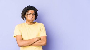 Genç Afrikalı Amerikalı Rasta adamın yanakları şişiyor, yorgun bir ifadesi var. Yüz ifadesi kavramı.