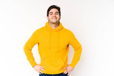 Beyaz arka planda izole edilmiş genç bir adam. Kendine güveniyor. Ellerini kalçasında tutuyor..