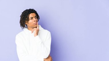 Genç Afrikalı Amerikalı Rasta adam şüpheli ve şüpheci bir ifadeyle yana bakıyor..