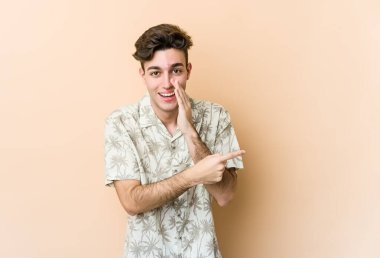 Beyaz tenli genç adam bej arka planda izole edilmiş. Dedikodu yapıyor, bir şeyleri bildiriyor..