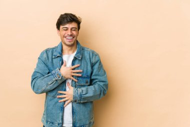 Genç havalı adam mutlu bir şekilde gülüyor ve ellerini karnının üstünde tutarak eğleniyor..