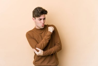 Kafkasyalı genç adam bej arka planda izole, kafası karışmış, şüpheli ve güvensiz hissediyor..