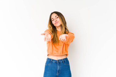 Beyaz arka planda izole edilmiş genç beyaz bir kadın dudaklarını katlıyor ve hava öpücüğü yollamak için avuç içleri tutuyor..