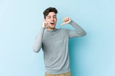 Mavi arka planda izole edilmiş genç beyaz adam gururlu ve kendinden emin hissediyor, örnek olarak.