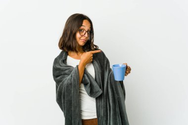 Beyaz arka planda battaniyeyle izole edilmiş genç Latin kadın işaret parmağıyla fotokopi alanını işaret ederek heyecan ve arzusunu ifade ediyor..